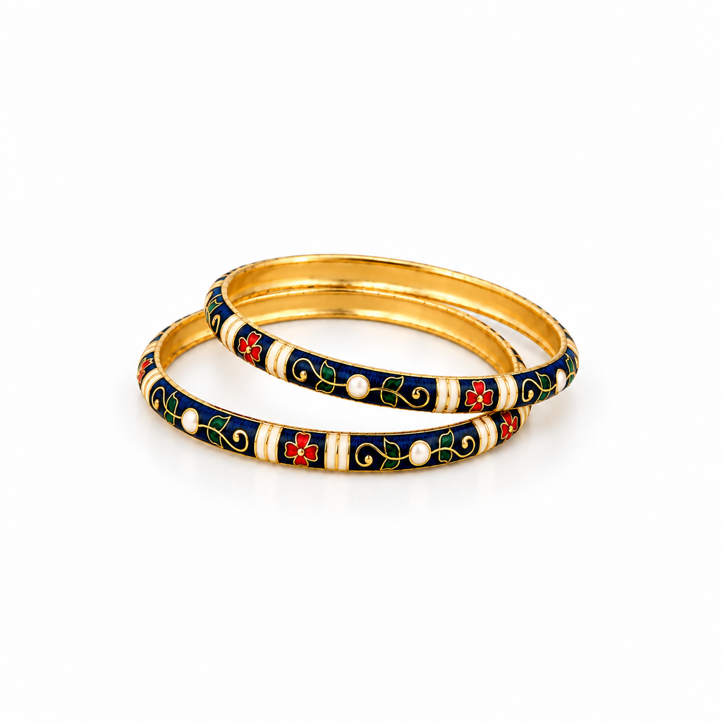 Two gold-plated bangles with dark blue, cream, and red floral enamel detailing, resting on a white marble surface.