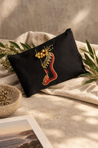 A black fabric pouch featuring an embroidered red and gold harp design, styled with green leaves on a plain white background.