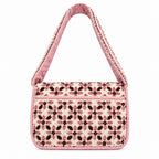 A small rectangular handbag with a pink and black patterned fabric body and a pink strap, photographed from above on a plain off-white background.