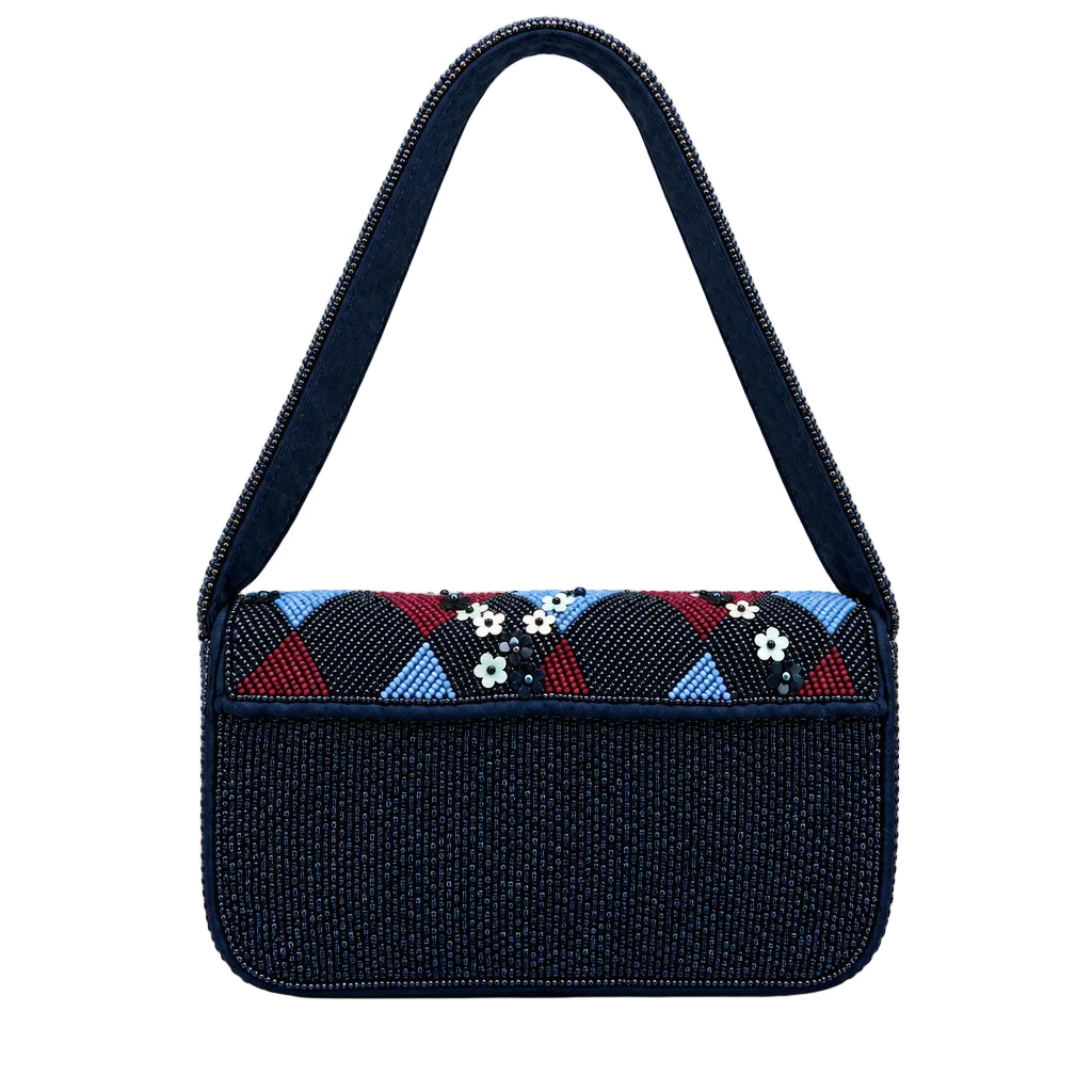 A dark navy blue shoulder bag with a wide, patterned top flap featuring geometric and floral designs in red, blue, white, and black, set against a white studio background.