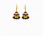 A pair of gold-toned traditional Indian jhumka earrings with black, cream, and maroon enamel detailing and dangling black beads, shown on a light cream background.