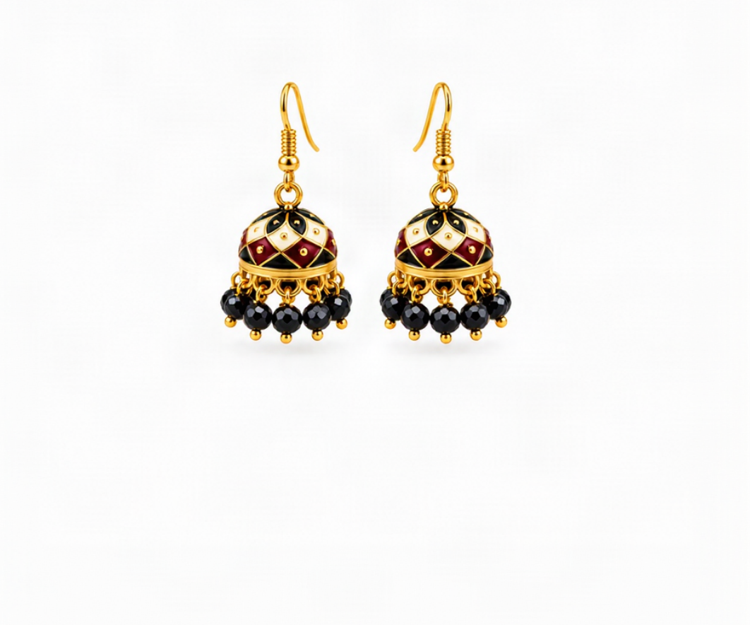 A pair of gold-toned traditional Indian jhumka earrings with black, cream, and maroon enamel detailing and dangling black beads, shown on a light cream background.