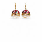 A pair of traditional Indian jhumka earrings with gold-plated frames, pink floral enamel, green and white accents, and dangling white pearl beads, shown on a white background.