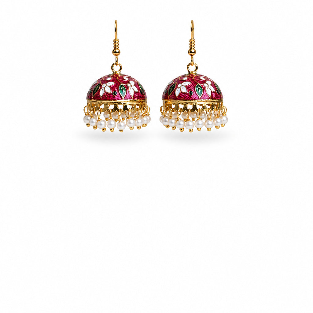 A pair of traditional Indian jhumka earrings with gold-plated frames, pink floral enamel, green and white accents, and dangling white pearl beads, shown on a white background.