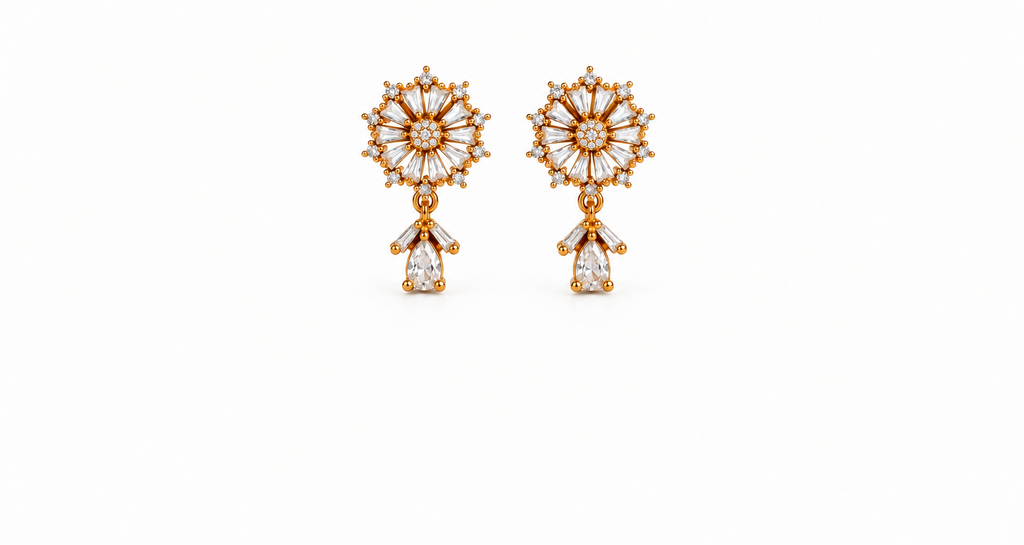 A pair of gold dangle earrings with intricate sunburst floral designs set with clear baguette and round gemstones, featuring pear-cut drop charms below, shown on a solid white background.