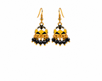A pair of traditional Indian gold-plated jhumka earrings with black and white enamel patterns, dangling black beads, and small gold bead accents, set against a plain light beige background.